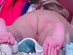 Nudist woman laid down on her belly sunbathing