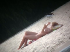 Spy cam shot of a hot nudist blond tanning on the beach