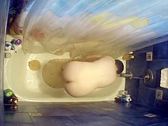Nude woman bending over in bathtub
